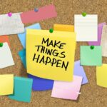 Bulletin Board with multicolored post-its pinned to it including a yellow one that reads, "Make Things Happen."